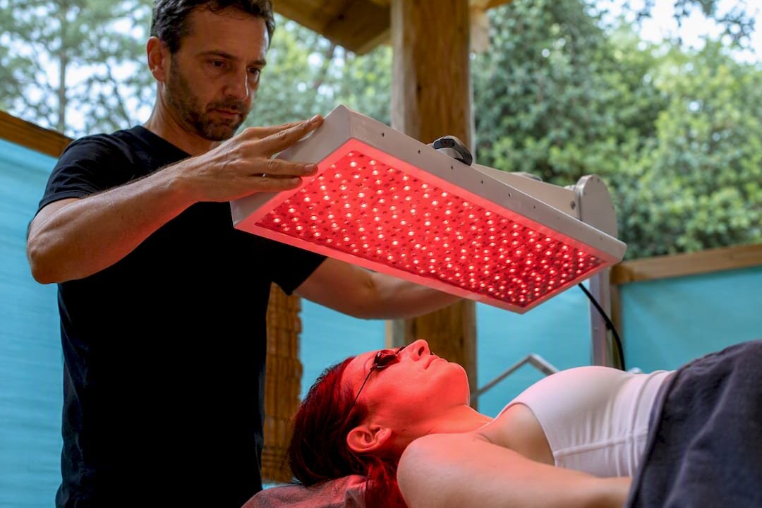 Hands adjusting red light therapy panel above head