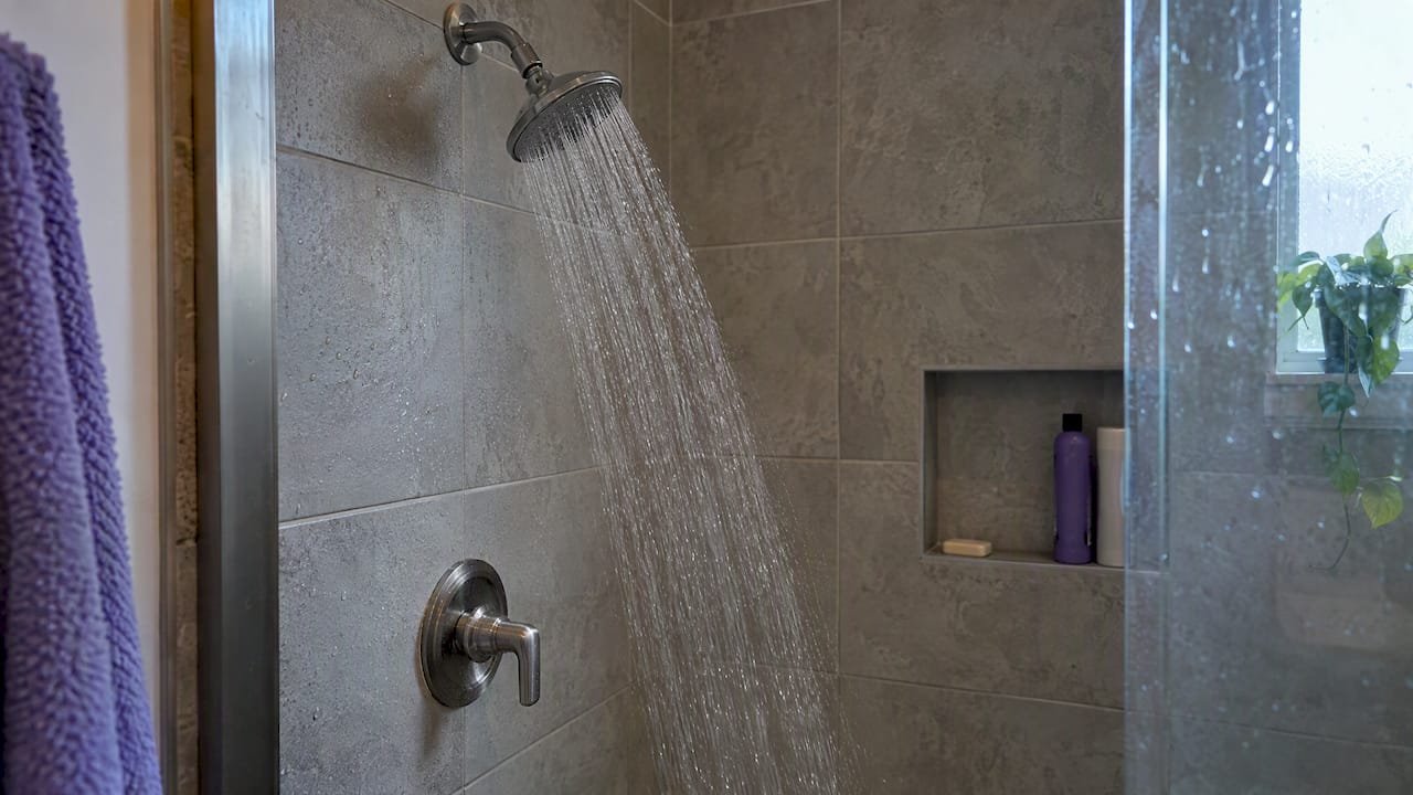 Warm shower running in a tiled bathroom